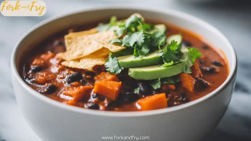 Hearty vegan chili with black beans and sweet potatoes in a white bowl.