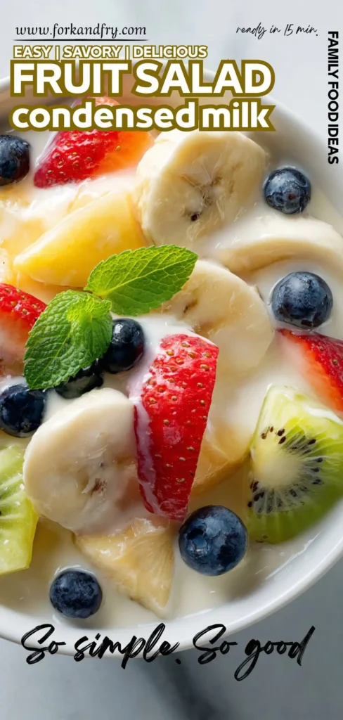 Creamy fruit salad served in a white bowl, topped with fresh berries and mint for garnish