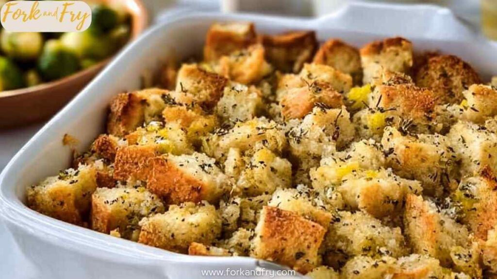 Golden baked bread stuffing with herbs in white casserole dish