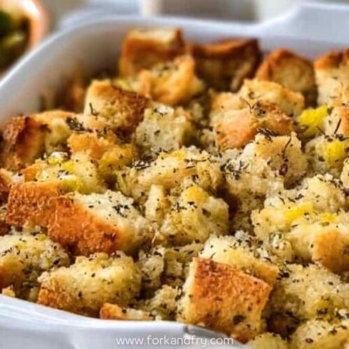 Golden baked bread stuffing with herbs in white casserole dish
