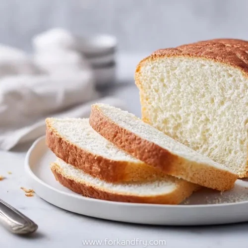 sliced white sandwich bread loaf on ceramic plate with knife and linen napkin