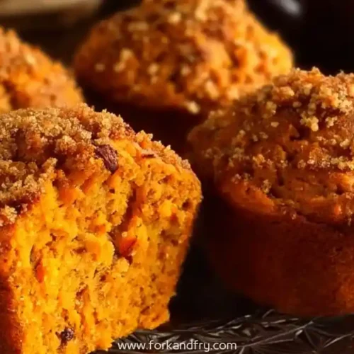 Freshly baked carrot cinnamon muffins with crumb topping on a dark plate
