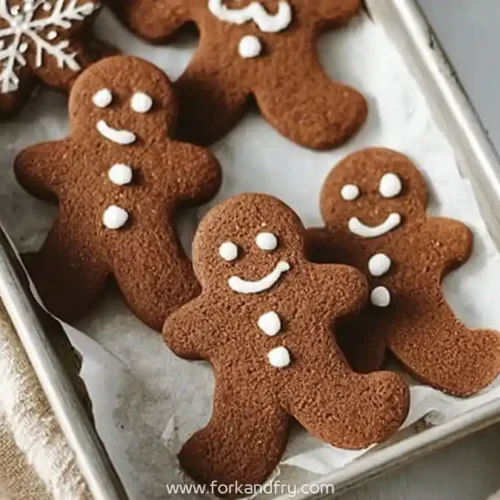 chocolate gingerbread cookies shaped like gingerbread men on a parchment-lined tray
