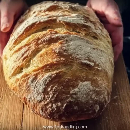 Round view of golden crusty homemade bread on cutting board