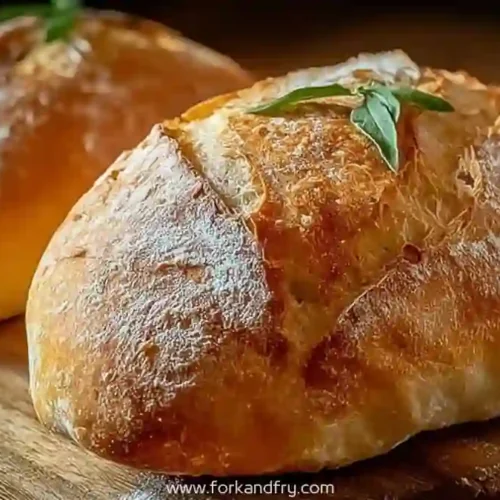Crusty golden Italian bread loaf with fresh basil on wooden board