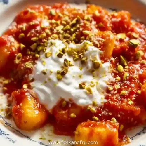 Soft gnocchi with rich tomato cream sauce, whipped ricotta, and crushed pistachios on vintage plate