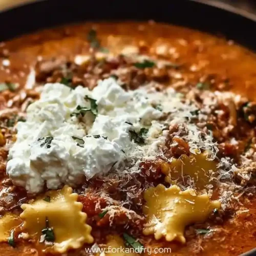 Bowl of lasagna soup topped with creamy ricotta, shredded cheese, and mini pasta, garnished with herbs in rich tomato broth
