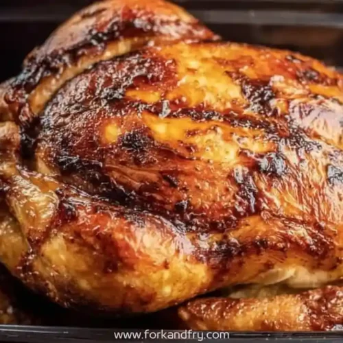 Whole rotisserie chicken with crispy golden skin in a black plastic container