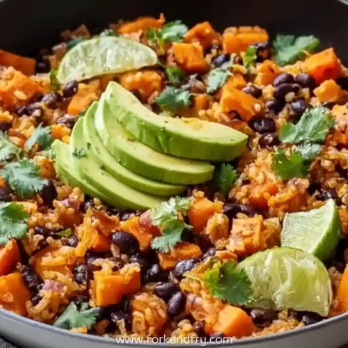 One-pan sweet potato black bean rice with avocado slices and lime wedges