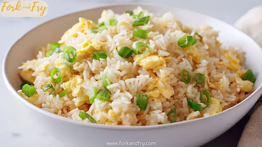 bowl of Chinese egg fried rice with green onions in a white bowl