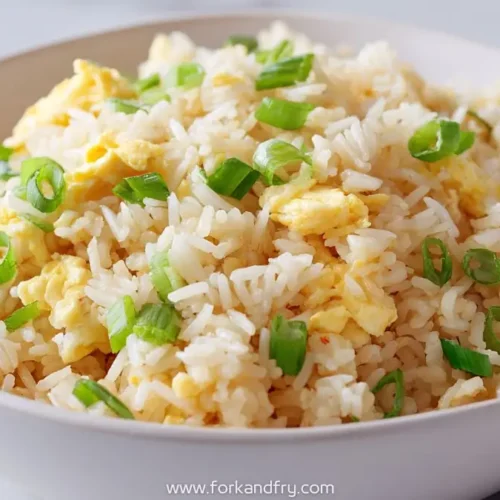 bowl of Chinese egg fried rice with green onions in a white bowl