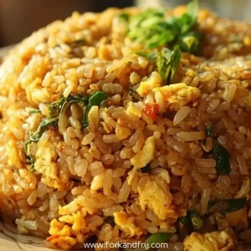 Golden fried rice with scrambled egg and green herbs shaped into a dome on a plate