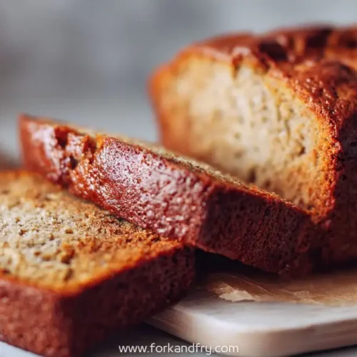 sliced golden banana bread made with sourdough discard on wooden board