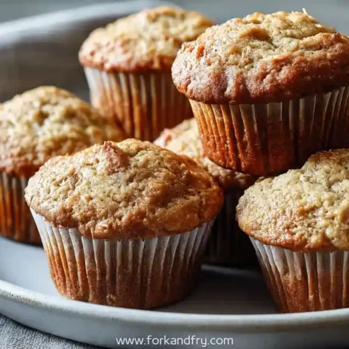 freshly baked banana almond muffins stacked on a ceramic plate