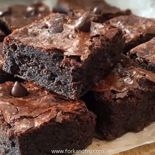 rich chocolate chip brownies stacked on parchment paper with gooey center