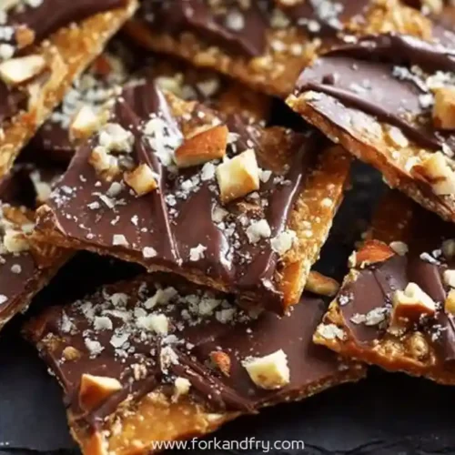 Crispy chocolate toffee bark topped with chopped almonds and sea salt on slate tray