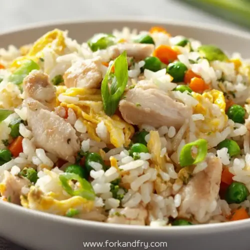 closeup of classic chicken fried rice with diced carrots, peas, scallions and egg in a white bowl