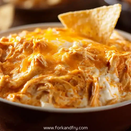 cheesy crockpot buffalo chicken dip in bowl with tortilla chip for scooping