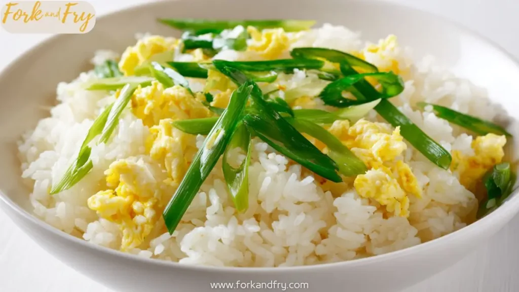 Fluffy egg fried rice topped with sliced scallions in a white bowl