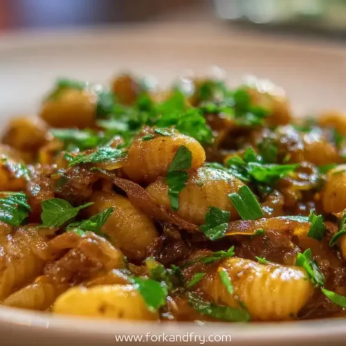 Creamy French onion pasta shells with caramelized onions and fresh parsley in a white bowl