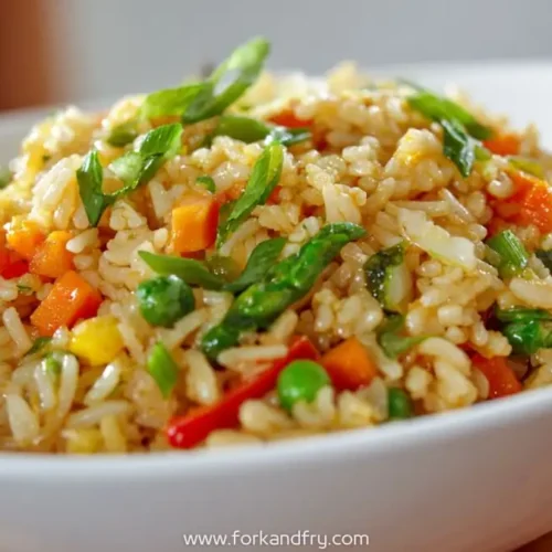 garlic butter vegetable fried rice with carrots, peas, bell peppers, and asparagus in a white bowl