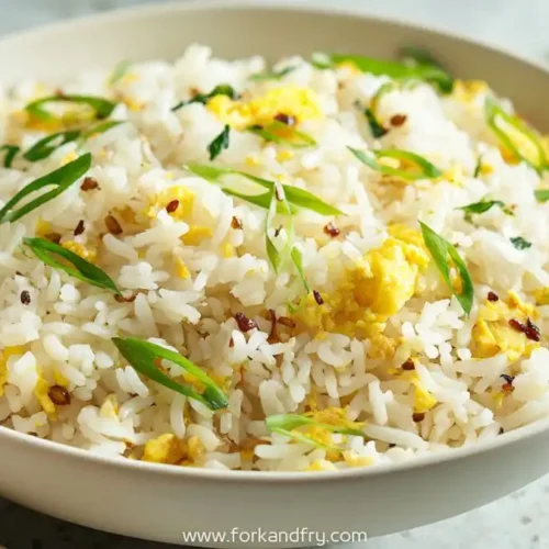 Garlic egg fried rice with scallions served in a white bowl