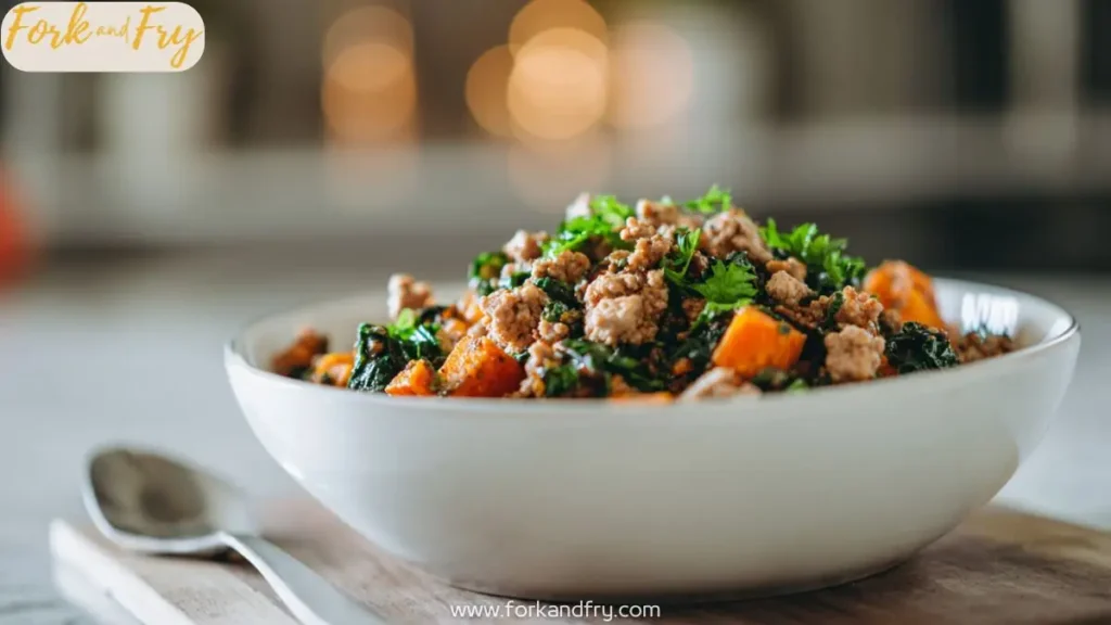 Bowl of ground turkey with sweet potatoes kale and parsley served warm on a wooden board