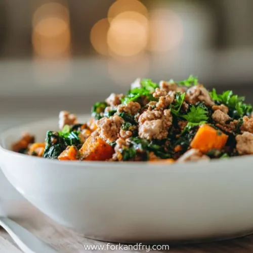 Bowl of ground turkey with sweet potatoes kale and parsley served warm on a wooden board