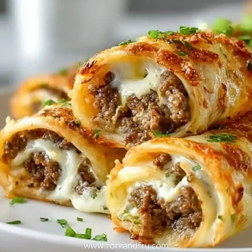 Cheesy keto Philly cheesesteak roll ups filled with beef and melted provolone on a white plate