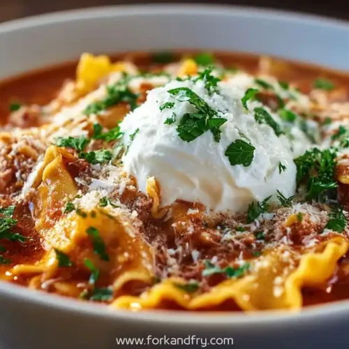 Bowl of hearty lasagna soup with pasta, marinara, fresh parsley, and a dollop of ricotta cheese
