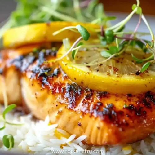 Grilled lemon butter cod fillet on white rice topped with lemon slices and microgreens