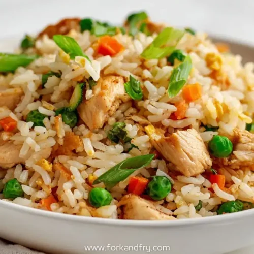 one pot chicken fried rice with diced carrots, peas, scallions and golden rice in a white bowl
