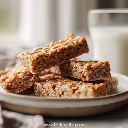 stack of peanut butter oat snack bars on ceramic plate with glass of milk in background