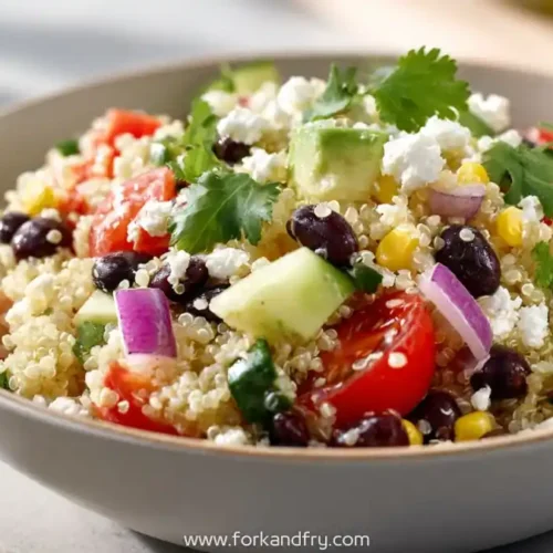 Quinoa salad with black beans, cherry tomatoes, cucumber, corn, red onion, feta, and cilantro in a bowl