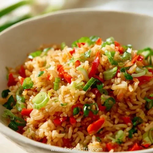 Spicy schezwan fried rice topped with chopped spring onions in a white ceramic bowl