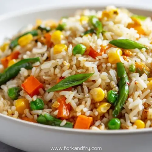 Colorful vegetable fried rice with carrots, peas, corn, green beans and scallions in a white bowl
