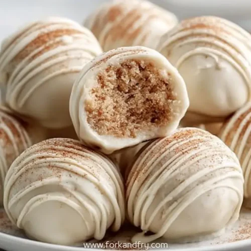 White chocolate cookie truffles stacked on plate with cinnamon and drizzle detail and bite showing inside texture