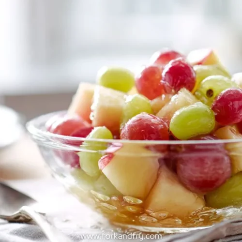 Glass bowl of fresh apple cubes with red and green grapes on folded napkin in bright setting