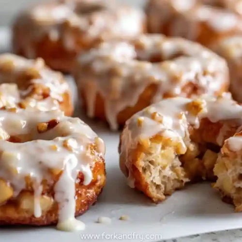 Glazed baked apple fritters with chopped apples on parchment paper