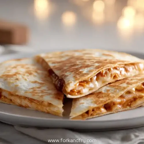 grilled bbq chicken quesadillas stacked on white plate with warm dinner lighting