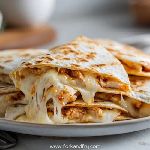 cheesy bbq chicken quesadillas stacked on plate with melty mozzarella stretch
