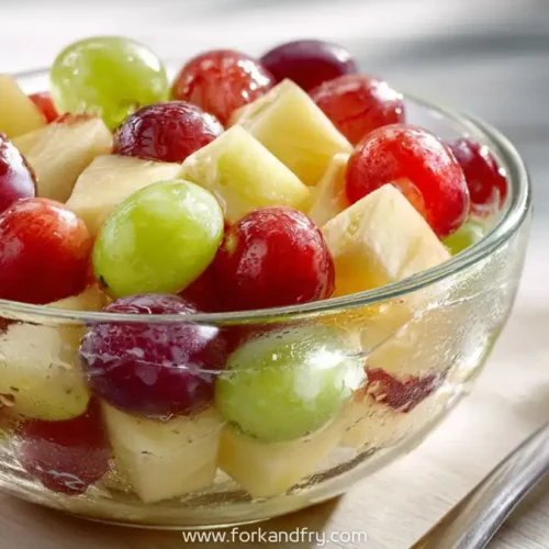 Glass bowl with red grapes, green grapes and apple cubes served chilled with visible condensation