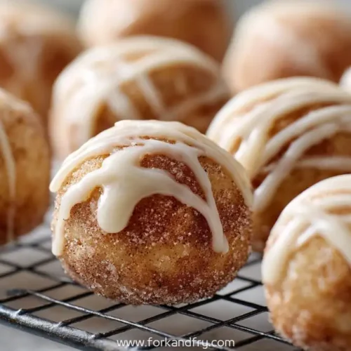 Cinnamon sugar donut holes with vanilla glaze on cooling rack, close-up