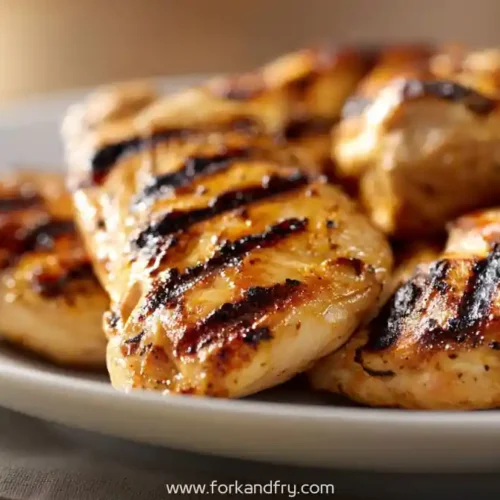 Close-up of grilled chicken breasts with citrus garlic seasoning on a white plate