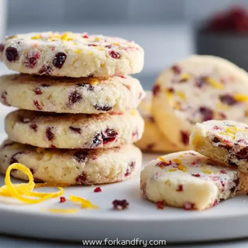 stack of cranberry citrus butter cookies with zest and dried berries on white plate
