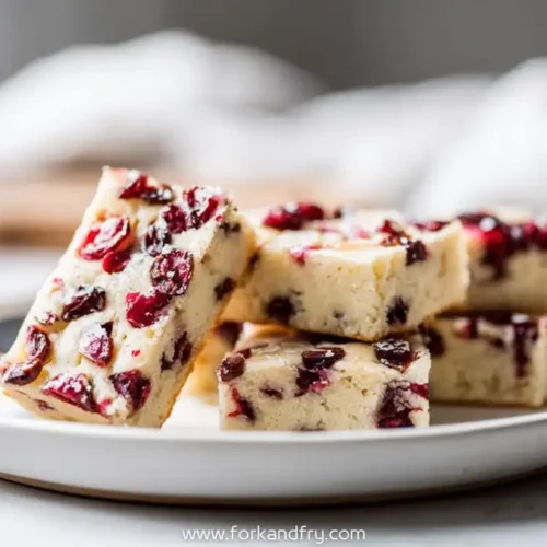 stacked cranberry orange cookie bars on a white plate with soft linen background