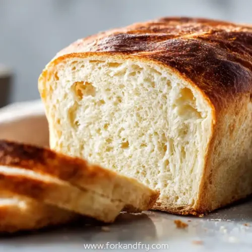 sliced loaf of no knead dutch oven sandwich bread on white surface