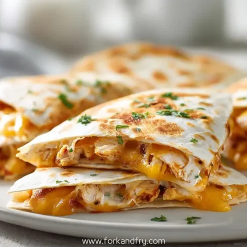 cheesy grilled chicken quesadillas stacked on plate with melted cheddar
