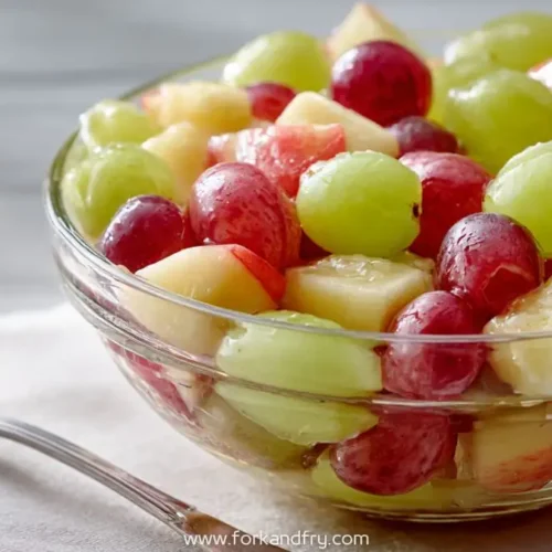 colorful fruit salad with grapes, apples, and melon in glass bowl on breakfast table