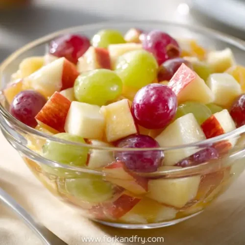 clear bowl filled with breakfast fruit salad of red grapes, green grapes, and apple chunks
